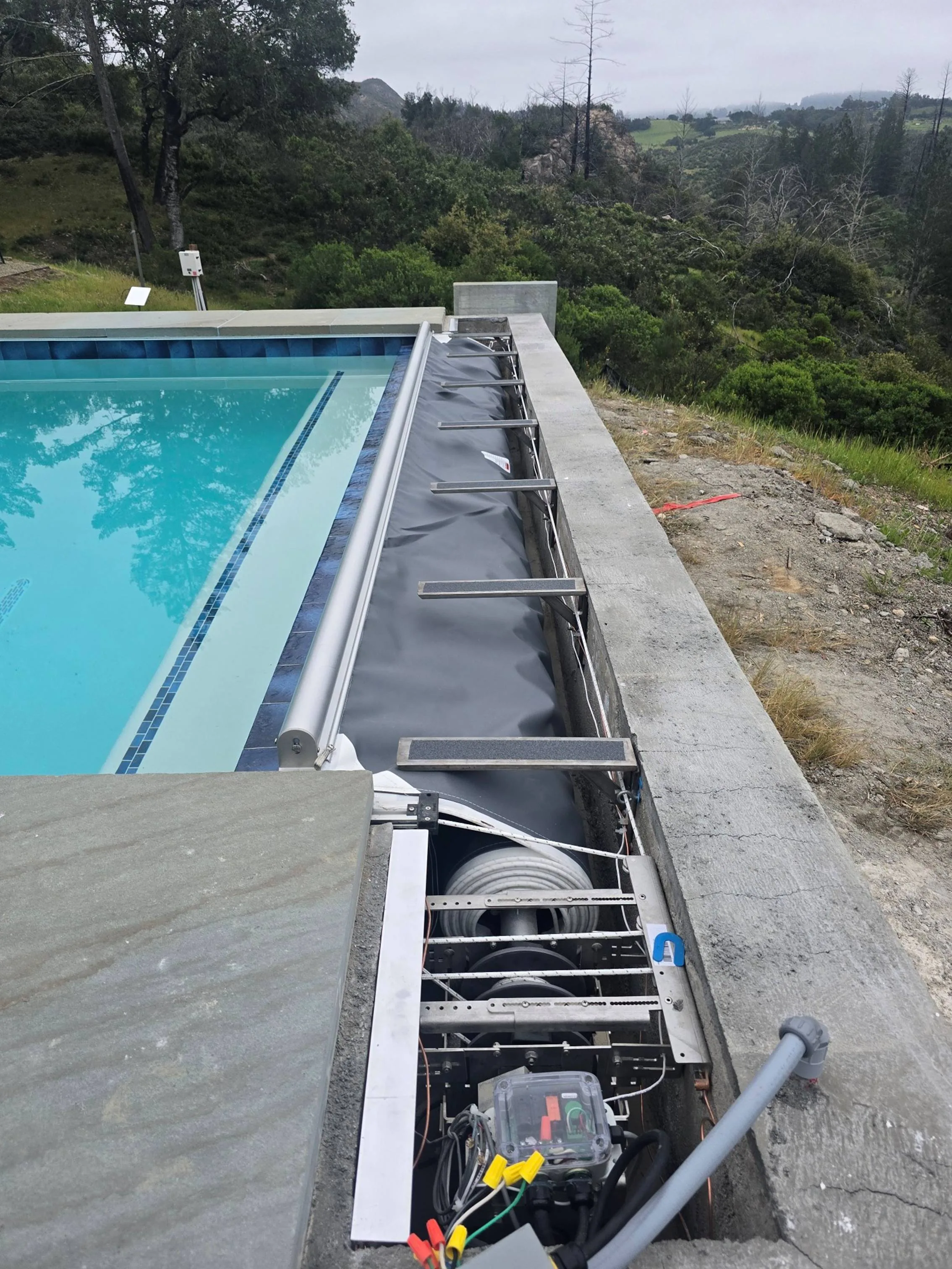 Split-drive automatic pool cover being installed on the raised Calistoga pool