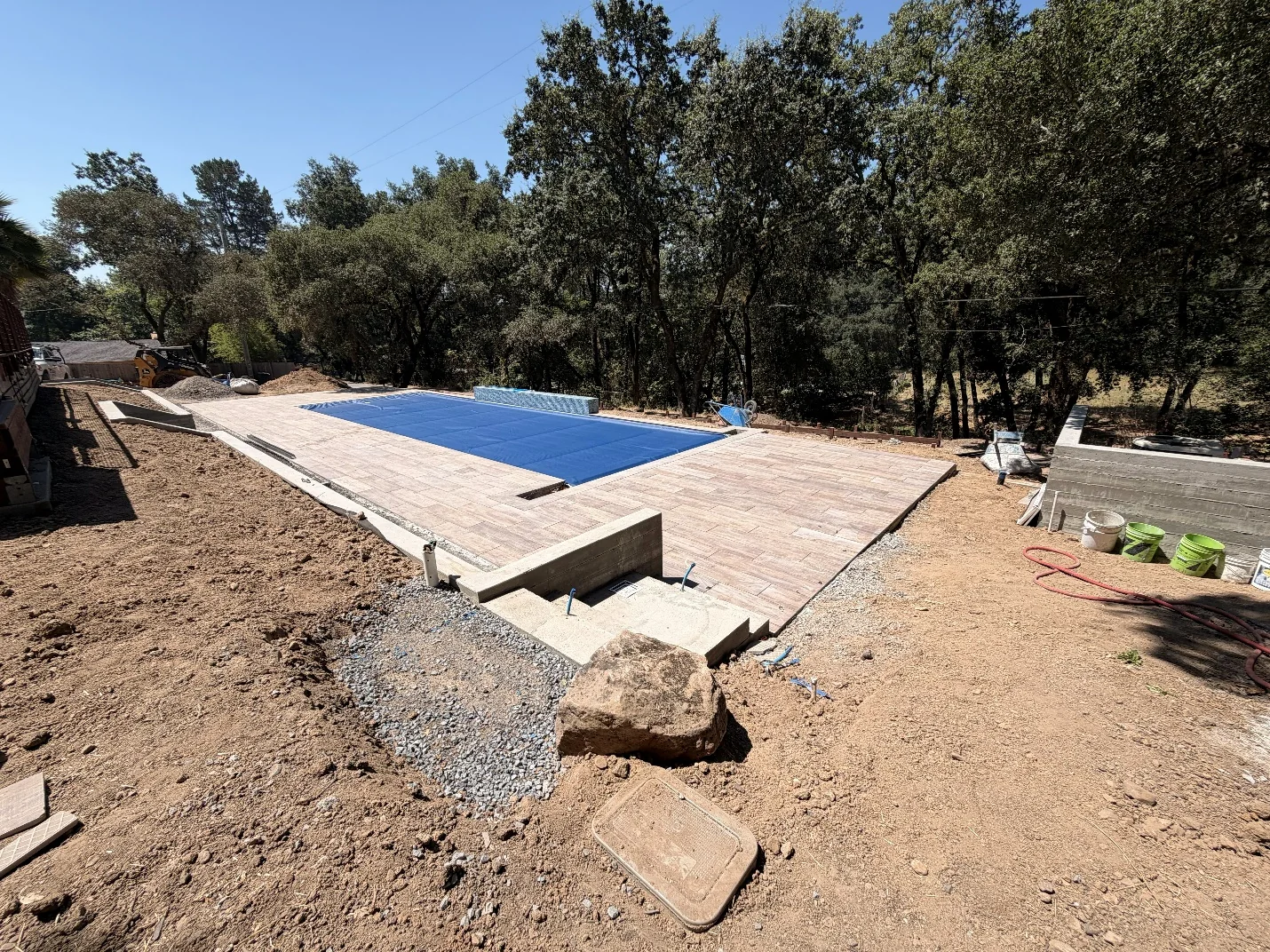 Raised pool and automatic cover under construction on a sloped lot