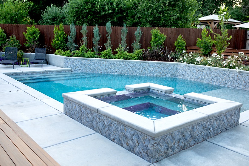 Custom shaped pool with a raised spa and a raised retaining wall for planters