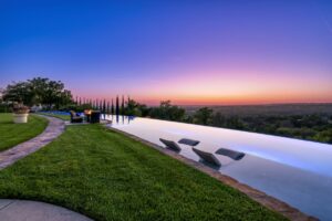 Long curved infinity edge pool with view of sunset