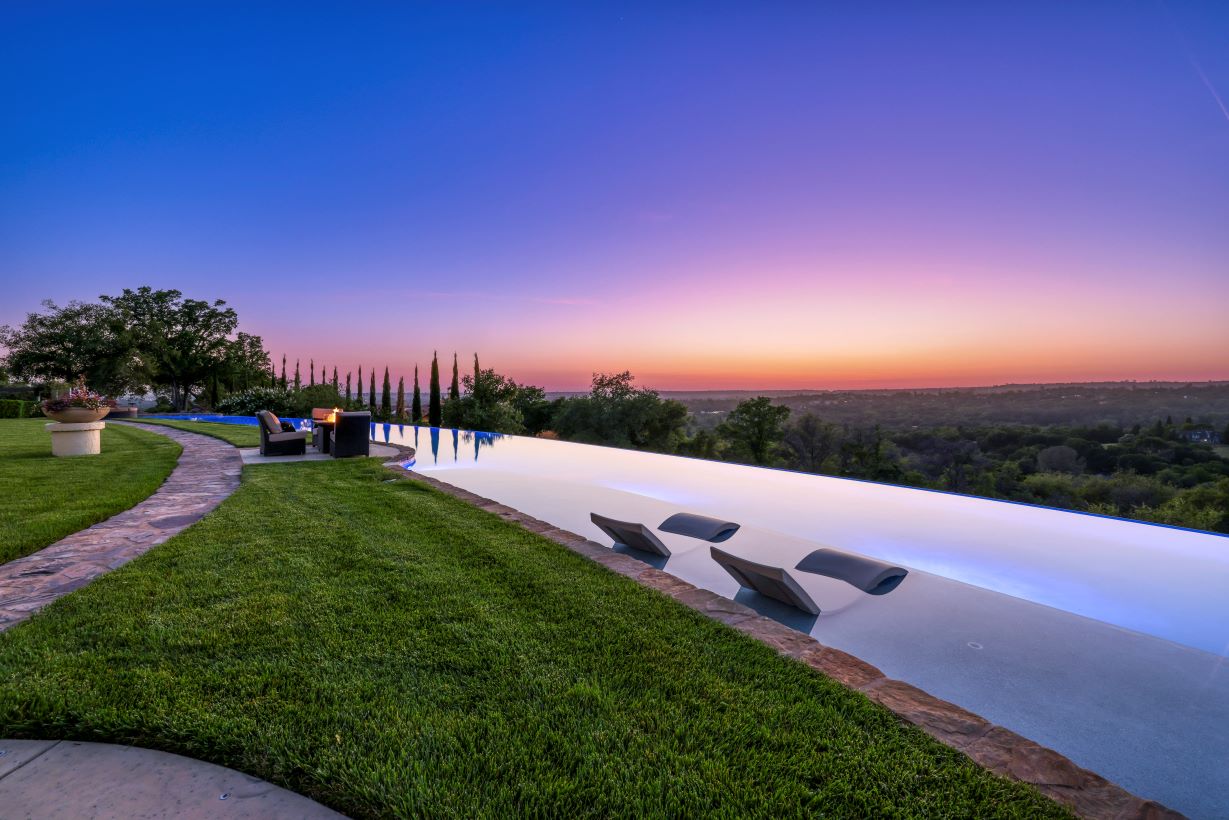 Long curved infinity edge pool with view of sunset