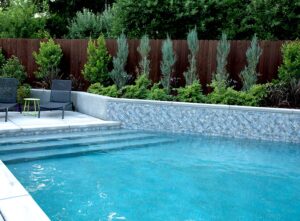 Custom shaped pool with a retaining wall for planters and long entry steps