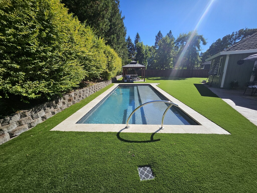 Swimming pool in Santa Rosa, California with an automatic pool cover, stone coping and turf